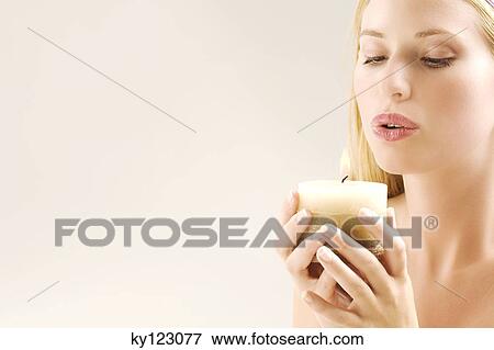 Portrait of a young woman blowing out candle in her hands, indoors (studio) View Large Photo Image Stock Photo - Portrait of a young woman blowing out candle in her hands, indoors (studio). Fotosearch
