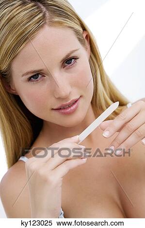 Portrait of a young woman filing her nails, indoors (studio) View Large Photo Image Stock Photography - Portrait of a young woman filing her nails, indoors (studio). Fotosearch