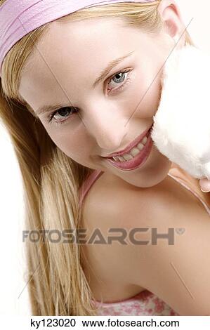 Portrait of a young woman holding a powder puff on her cheek, indoors (studio) View Large Photo Image Stock Image - Portrait of a young woman holding a powder puff on her cheek, indoors (studio). Fotosearch