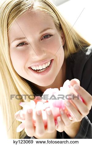 Portrait of a young woman holding petals flowers, indoors (studio) View Large Photo Image Stock Photo - Portrait of a young woman holding petals flowers, indoors (studio). Fotosearch