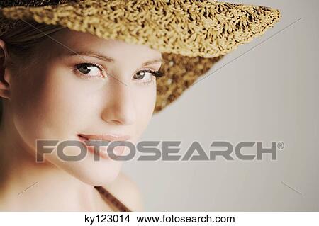 Portrait of a young woman looking at the camera, straw hat, indoors (studio) View Large Photo Image Picture - Portrait of a young woman looking at the camera, straw hat, indoors (studio). Fotosearch