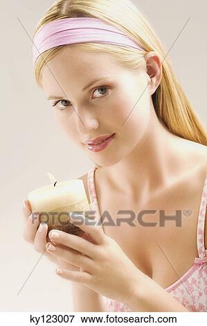 Stock Photo - Portrait of a young woman looking at the camera, holding a candle, indoors (studio). Fotosearch