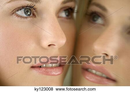 Portrait of a young woman looking at herself in a mirror View Large Photo Image Stock Photo - Portrait of a young woman looking at herself in a mirror. Fotosearch
