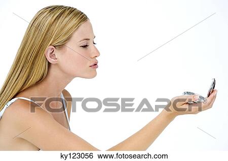 Portrait of a young woman looking at herself in a little miror, indoors (studio) View Large Photo Image Stock Photograph - Portrait of a young woman looking at herself in a little miror, indoors (studio). Fotosearch