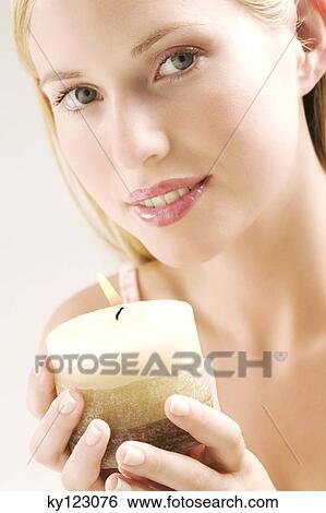 Portrait of a young woman looking at the camera, holding a candle, indoors (studio) View Large Photo Image Stock Photograph - Portrait of a young woman looking at the camera, holding a candle, indoors (studio). Fotosearch