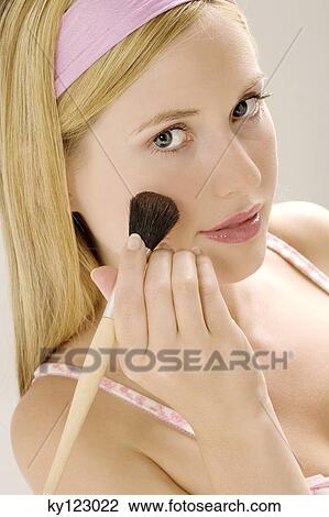 Portrait of a young woman making-up her cheek with a brush, indoors (studio) View Large Photo Image Stock Image - Portrait of a young woman making-up her cheek with a brush, indoors (studio). Fotosearch