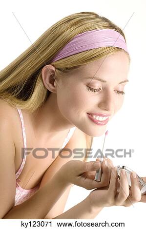 Stock Image - Portrait of a young woman making-up her mouth, indoors (studio). Fotosearch