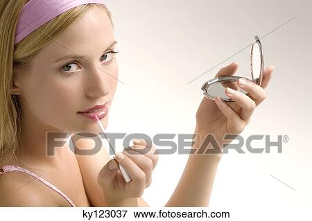Stock Photo - Portrait of a young woman making-up her mouth, indoors (studio). Fotosearch