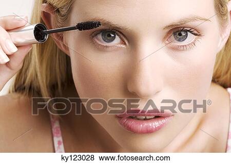 Portrait of a young woman making-up with mascara, indoors (studio) View Large Photo Image Stock Photo - Portrait of a young woman making-up with mascara, indoors (studio). Fotosearch