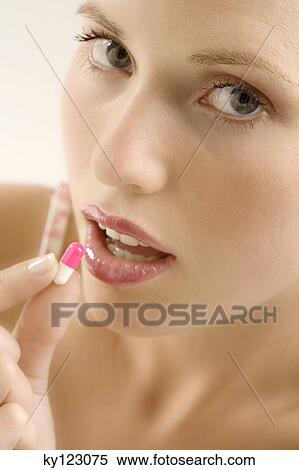 Portrait of a young woman opening her mouth for a capsule, indoors (studio) View Large Photo Image Stock Photography - Portrait of a young woman opening her mouth for a capsule, indoors (studio). Fotosearch