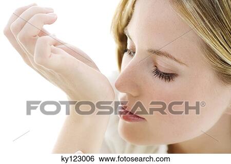 Portrait of a young woman smelling her wrist View Large Photo Image Stock Photograph - Portrait of a young woman smelling her wrist. Fotosearch