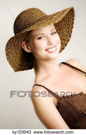Portrait of a young woman smiling, looking at the camera, brown top, straw hat, indoors (studio) View Large Photo Image Stock Image - Portrait of a young woman smiling, looking at the camera, brown top, straw hat, indoors (studio). Fotosearch