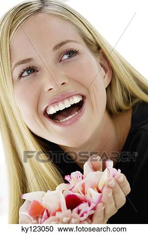 Portrait of a young woman smiling, holding petals flowers, indoors (studio) View Large Photo Image Stock Image - Portrait of a young woman smiling, holding petals flowers, indoors (studio). Fotosearch