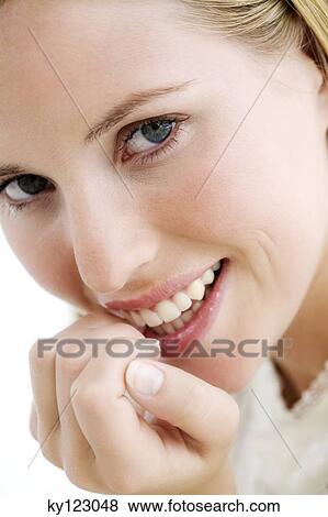 Stock Photo - Portrait of a young woman smiling, lookig at the camera, indoors (studio). Fotosearch