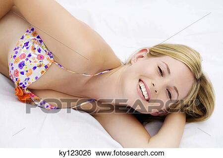 Portrait of a young woman smiling, lying, indoors (studio) View Large Photo Image Stock Photograph - Portrait of a young woman smiling, lying, indoors (studio). Fotosearch