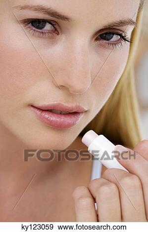Portrait of a young woman using a lip balm View Large Photo Image Stock Photo - Portrait of a young woman using a lip balm. Fotosearch