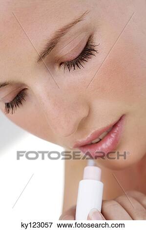 Portrait of a young woman using lip balm View Large Photo Image Stock Photo - Portrait of a young woman using lip balm. Fotosearch