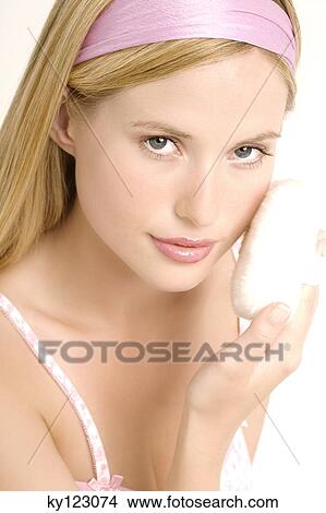 Portrait of a young woman with powder puff on her cheek, indoors (studio) View Large Photo Image Picture - Portrait of a young woman with powder puff on her cheek, indoors (studio). Fotosearch