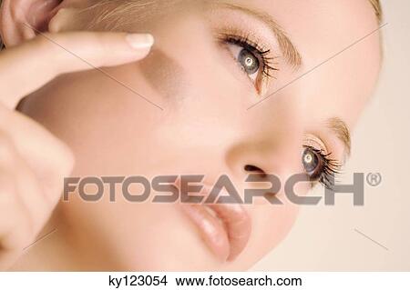 Woman putting make-up base on her cheek, close-up, indoors (studio) View Large Photo Image Picture - Woman putting make-up base on her cheek, close-up, indoors (studio). Fotosearch