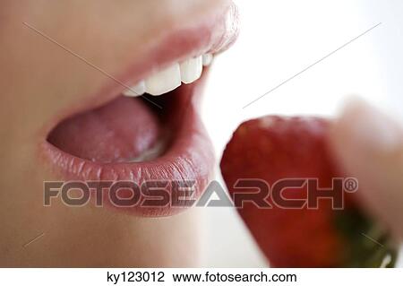 Young woman face eating a strawberry, close-up, indoors, studio View Large Photo Image Stock Image - Young woman face eating a strawberry, close-up, indoors, studio. Fotosearch