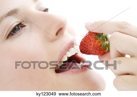 Young woman face eating a strawberry, close-up, indoors, studio View Large Photo Image Stock Photo - Young woman face eating a strawberry, close-up, indoors, studio. Fotosearch