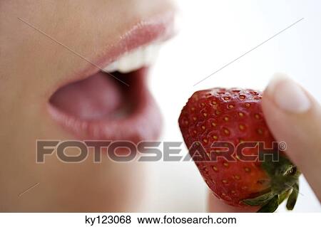 Young woman face eating a strawberry, close-up, indoors, studio View Large Photo Image Stock Photo - Young woman face eating a strawberry, close-up, indoors, studio. Fotosearch