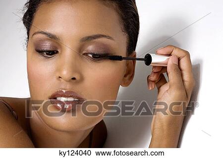 Stock Image - Portrait of a woman applying mascara. Fotosearch