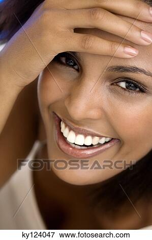 Portrait of a young smiling woman, hand on forehead View Large Photo Image Stock Photo - Portrait of a young smiling woman, hand on forehead. Fotosearch
