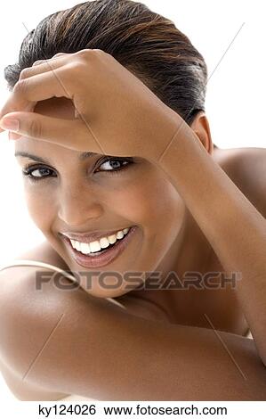 Stock Photograph - Portrait of a young smiling woman, hand on forehead. Fotosearch