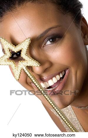 Stock Image - Portrait of a young smiling woman looking through magic wand. Fotosearch