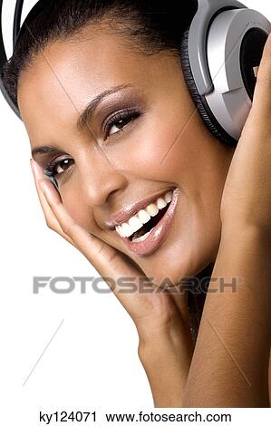 Stock Image - Portrait of a young smiling woman, listening to music with headphones. Fotosearch