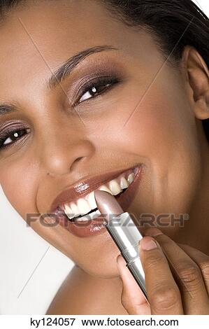Portrait of a young smiling woman, applying lipstick View Large Photo Image Stock Photo - Portrait of a young smiling woman, applying lipstick. Fotosearch