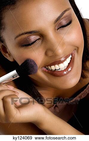 Portrait of a young smiling woman applying blush View Large Photo Image Stock Photo - Portrait of a young smiling woman applying blush. Fotosearch