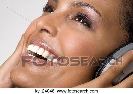 Stock Photograph - Portrait of a young smiling woman, listening to music with headphones. Fotosearch