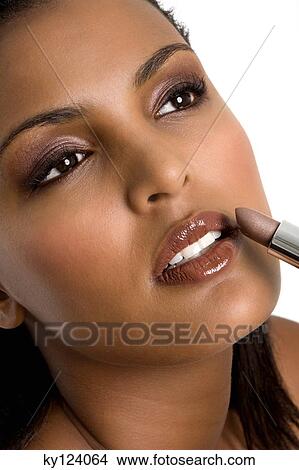 Picture - Portrait of a young woman applying lipstick. Fotosearch