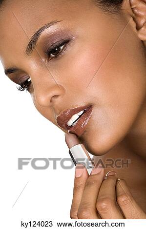 Portrait of a young woman applying lipstick View Large Photo Image Stock Image - Portrait of a young woman applying lipstick. Fotosearch