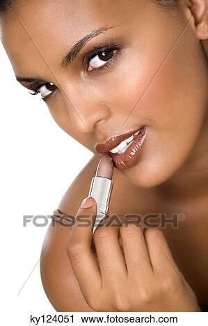 Portrait of a young woman applying lipstick View Large Photo Image Stock Image - Portrait of a young woman applying lipstick. Fotosearch