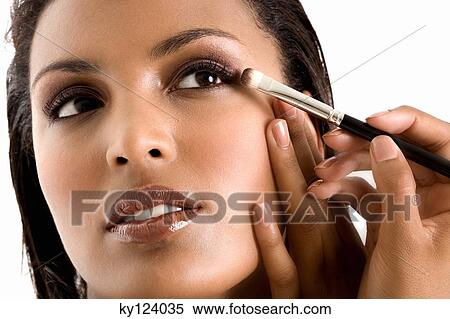 Stock Photography - Portrait of a young woman applying eyeshadow. Fotosearch