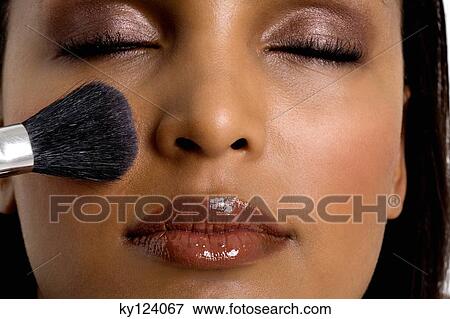 Stock Photo - Young woman applying blush. Fotosearch
