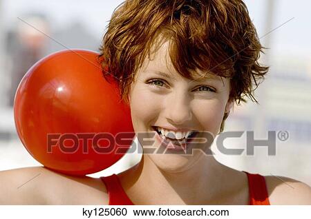 Portrait of a young smiling woman, red ball on shoulder View Large Photo Image Stock Image - Portrait of a young smiling woman, red ball on shoulder. Fotosearch