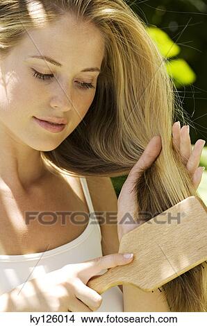 Portrait of a young blond woman brushing her hair, outdoors View Large Photo Image Picture - Portrait of a young blond woman brushing her hair, outdoors. Fotosearch
