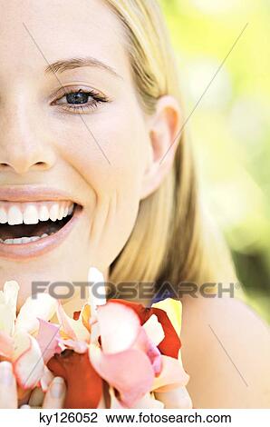 Portrait of a young blond woman smiling, holding petals, outdoors View Large Photo Image Stock Image - Portrait of a young blond woman smiling, holding petals, outdoors. Fotosearch
