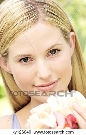 Portrait of a young blond woman smiling, holding petals, outdoors View Large Photo Image Stock Photo - Portrait of a young blond woman smiling, holding petals, outdoors. Fotosearch