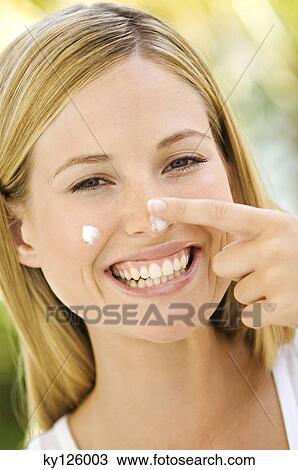 Portrait of a young woman applying moisturizer on her face, outdoors View Large Photo Image Stock Image - Portrait of a young woman applying moisturizer on her face, outdoors. Fotosearch