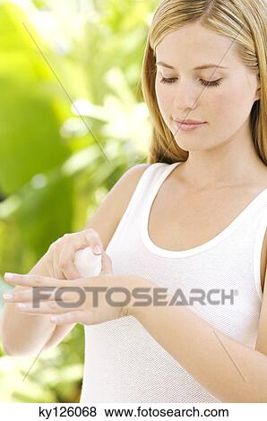 Portrait of a young woman applying moisturizer on her hand View Large Photo Image Stock Photo - Portrait of a young woman applying moisturizer on her hand. Fotosearch