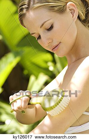 Portrait of a young woman brushing her arm, outdoors View Large Photo Image Stock Photo - Portrait of a young woman brushing her arm, outdoors. Fotosearch