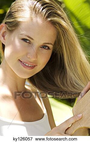 Portrait of a young woman brushing her hair, outdoors View Large Photo Image Stock Photo - Portrait of a young woman brushing her hair, outdoors. Fotosearch
