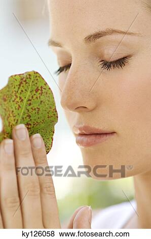 Portrait of a young woman, eyes shut, holding a little leaf, outdoors View Large Photo Image Stock Photo - Portrait of a young woman, eyes shut, holding a little leaf, outdoors. Fotosearch