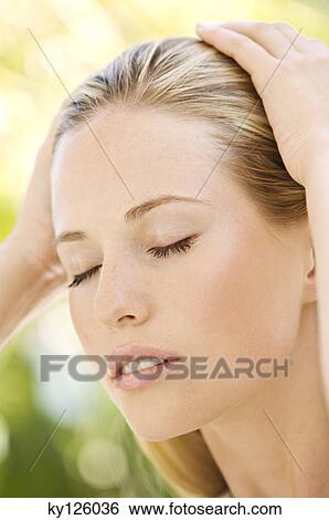 Portrait of a young woman, eyes shut, hands on her head, outdoors View Large Photo Image Stock Photograph - Portrait of a young woman, eyes shut, hands on her head, outdoors. Fotosearch