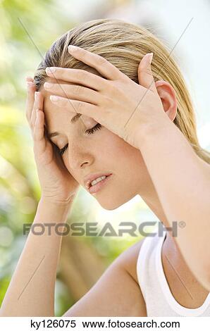 Stock Photography - Portrait of a young woman, eyes shut, hands on her head, outdoors. Fotosearch